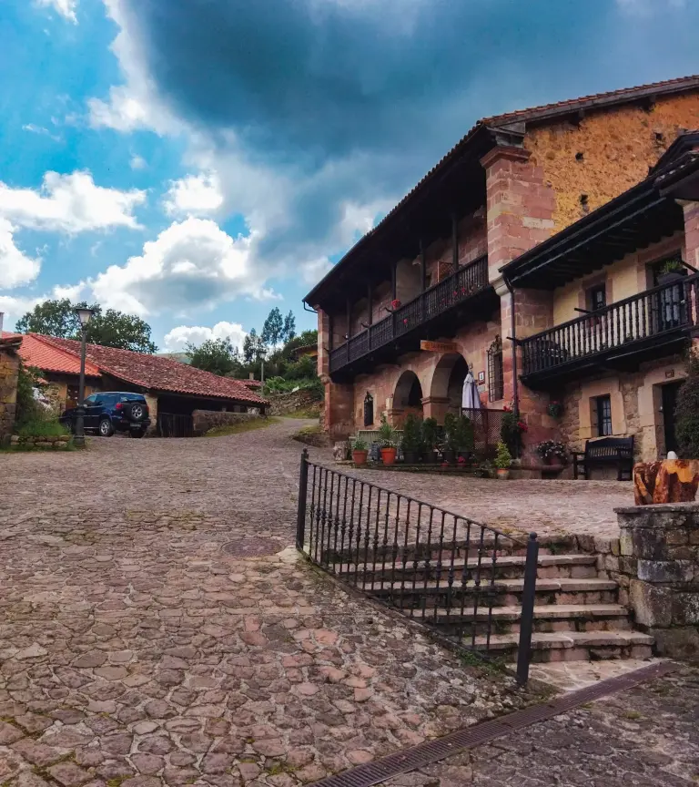 Casa Carmona, casona de piedra con balcones en una calle empedrada de Cantabria