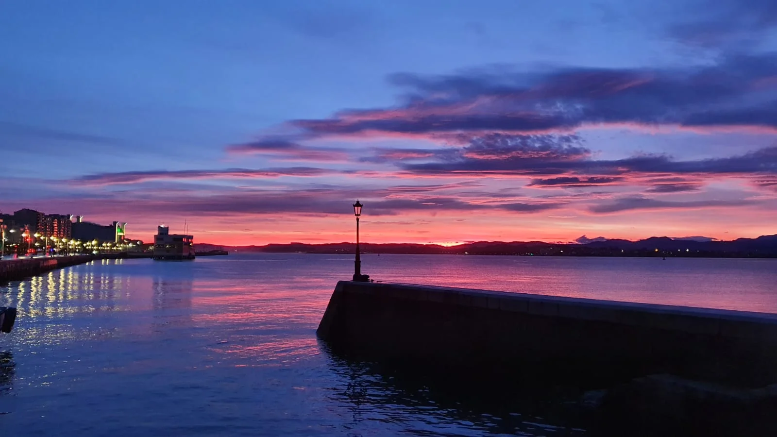 Bahía de Santander al amanecer con una farola en medio del espigón