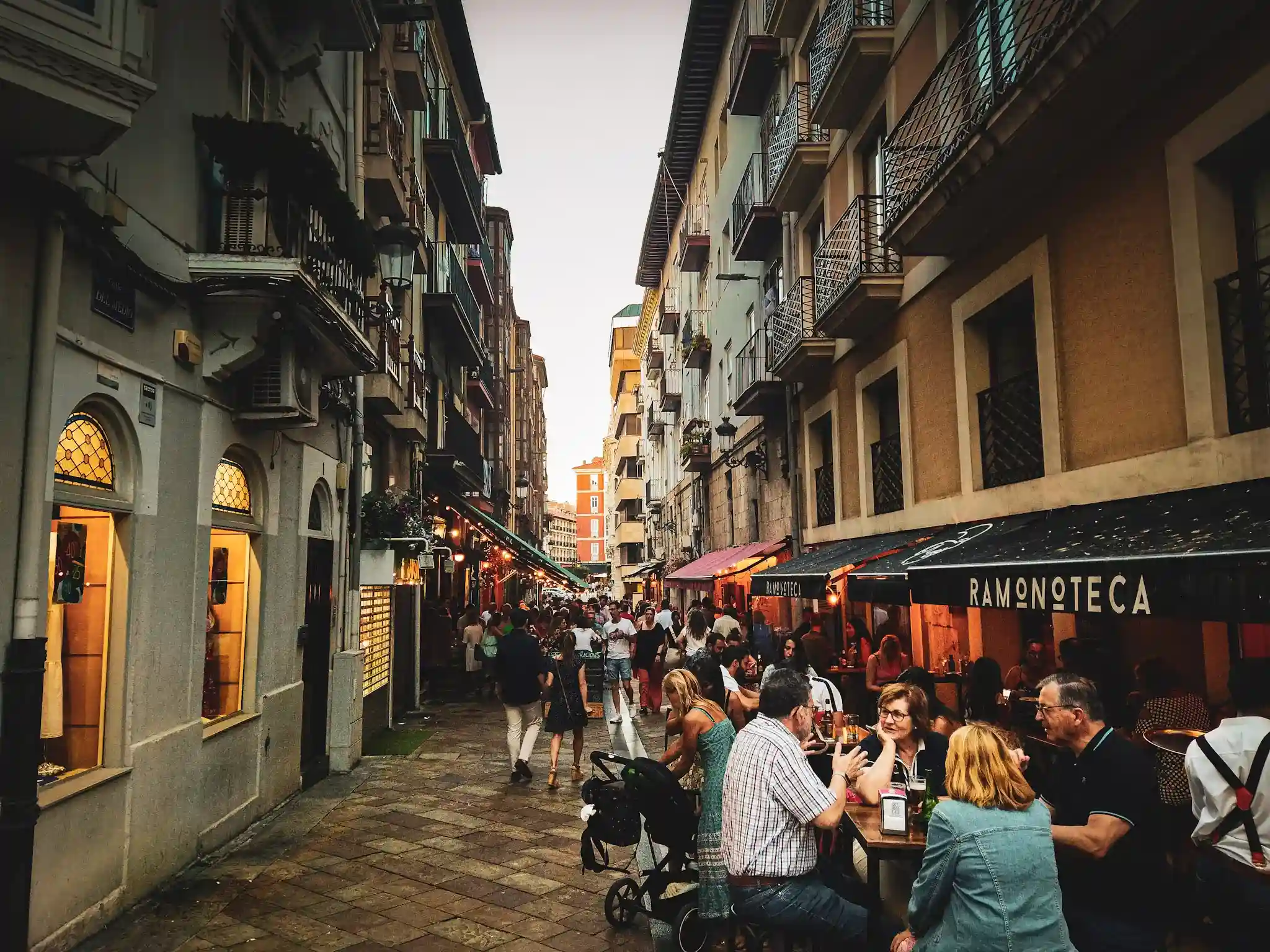 Calle estrecha con bares a los lados y multitud de gente