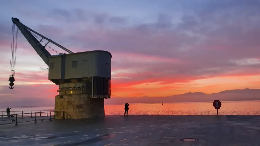 Grúa de piedra al amanecer con una persona sacando una foto.