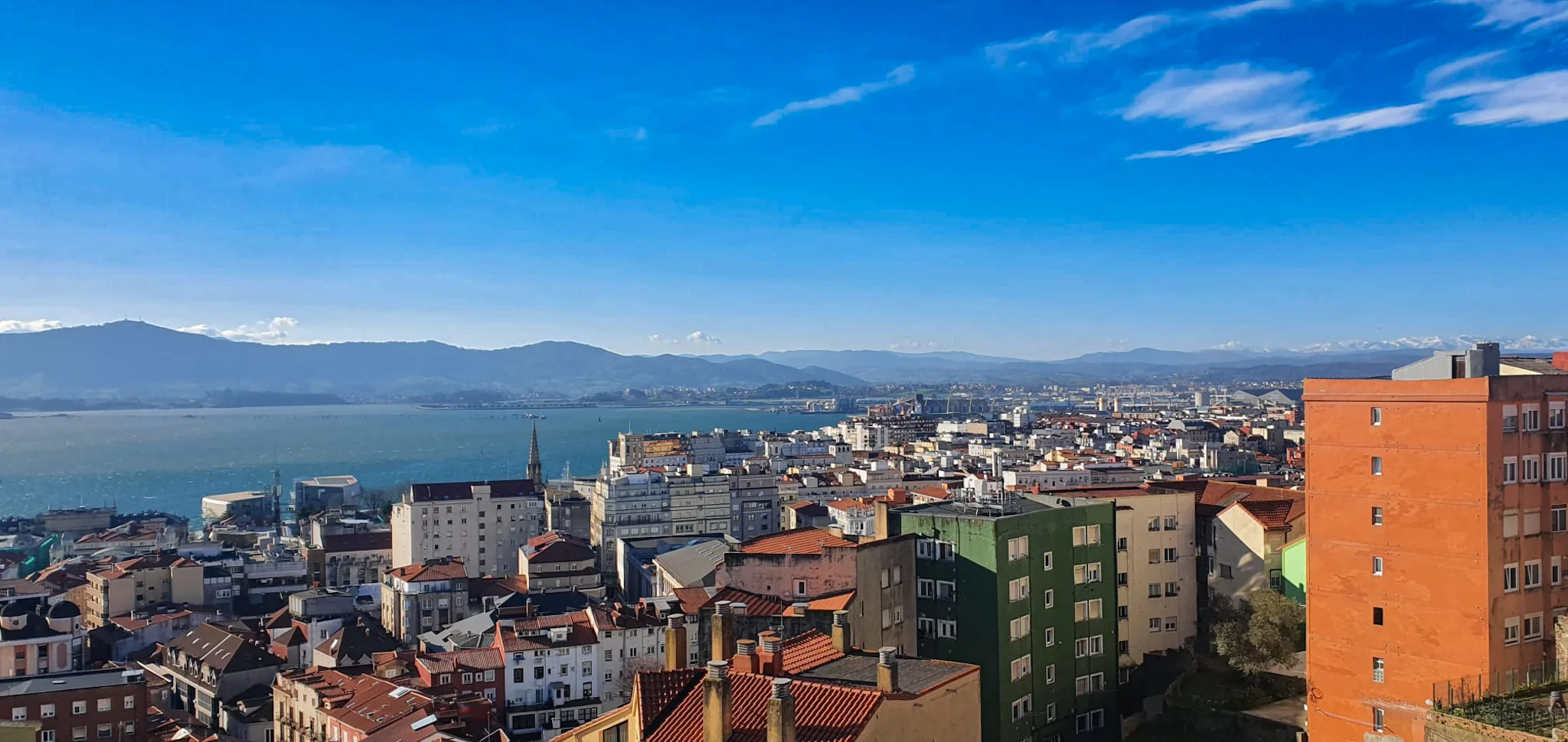 Montones de edificios con montañas al fondo y cielo completamente azul