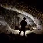 Hombre con una linterna alumbrando la cueva del moro Chufín en Cantabria
