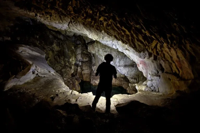 Hombre con una linterna alumbrando la cueva del moro Chufín en Cantabria