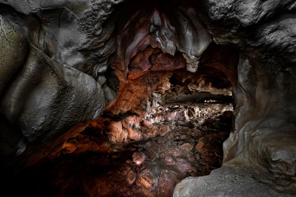 Cueva con rocas de diferentes colores y luz al final de la misma