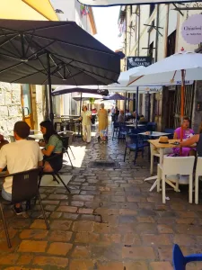 Calle estrecha empedrada con terrazas de bares a los lados