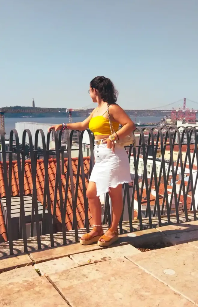 Chica apoyada en una barandilla con cientos de casas al fondo