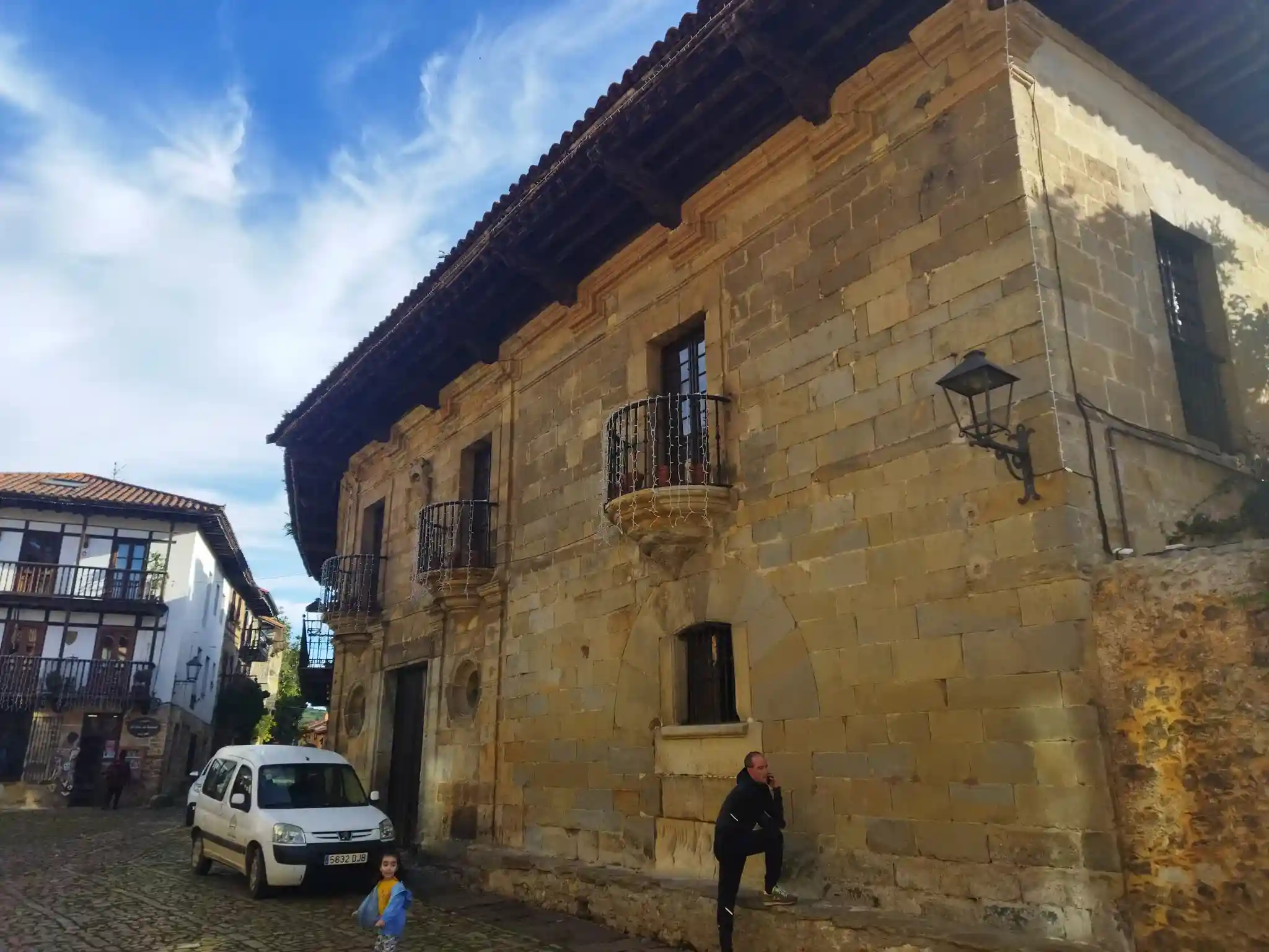 Edificio de piedra de sillería con un coche blanco en la puerta