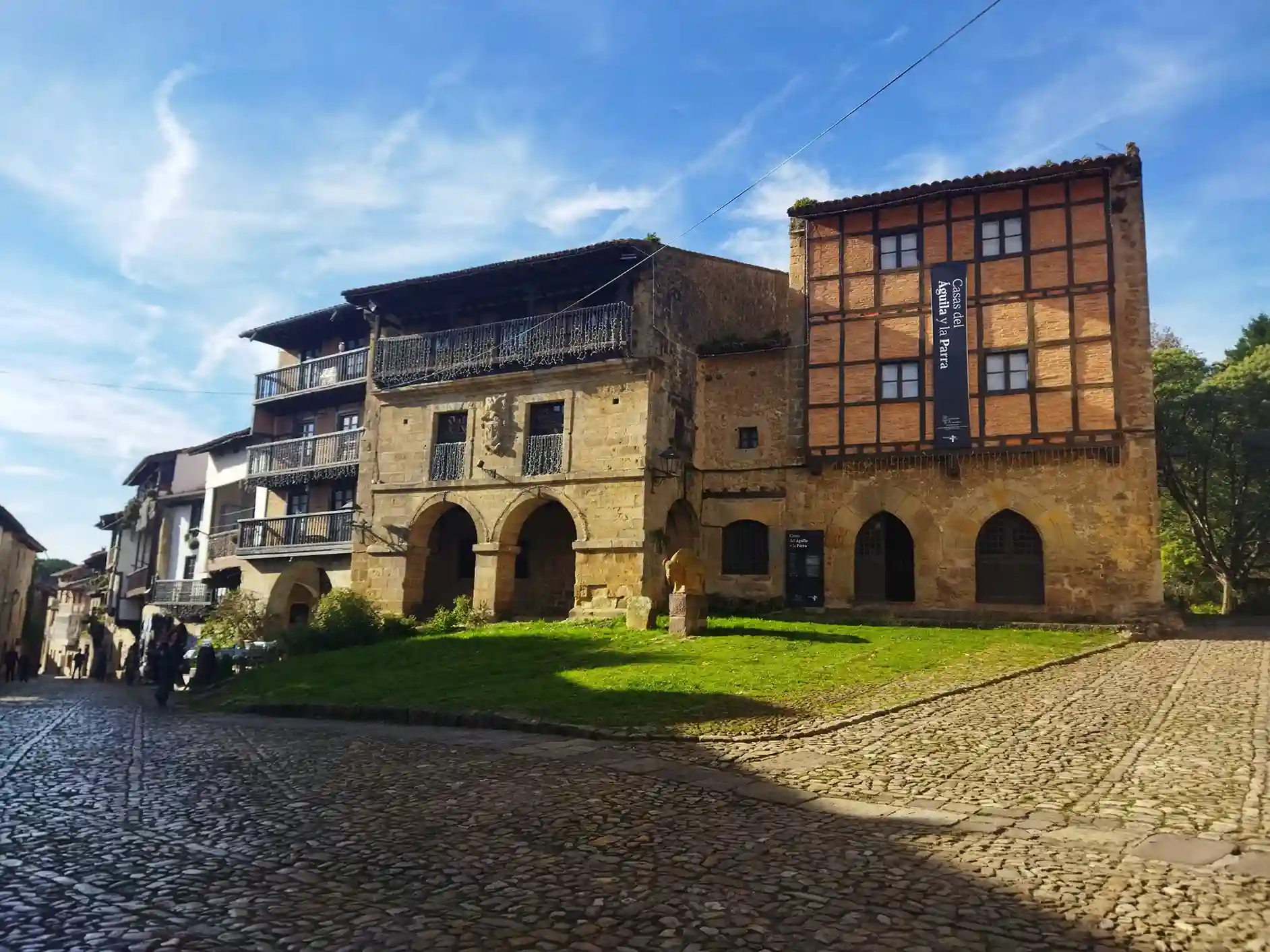 conjunto de edificios de piedra de sillería. Uno de ellos de color de ladridllo y suelo empedrado en Santillana del Mar