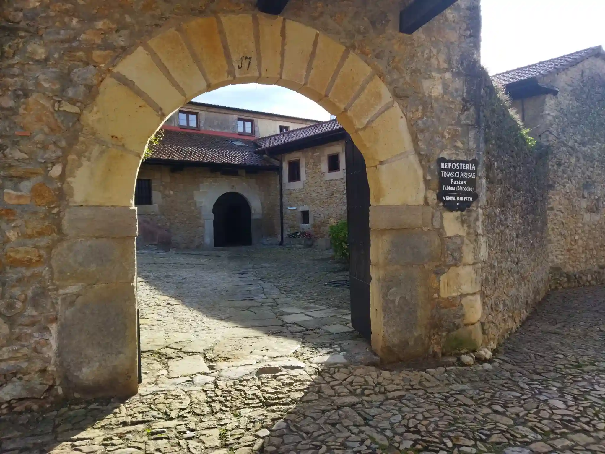 Arco de piedra de sillería en el primer plano y un conjunto de edificios de piedra al fondo