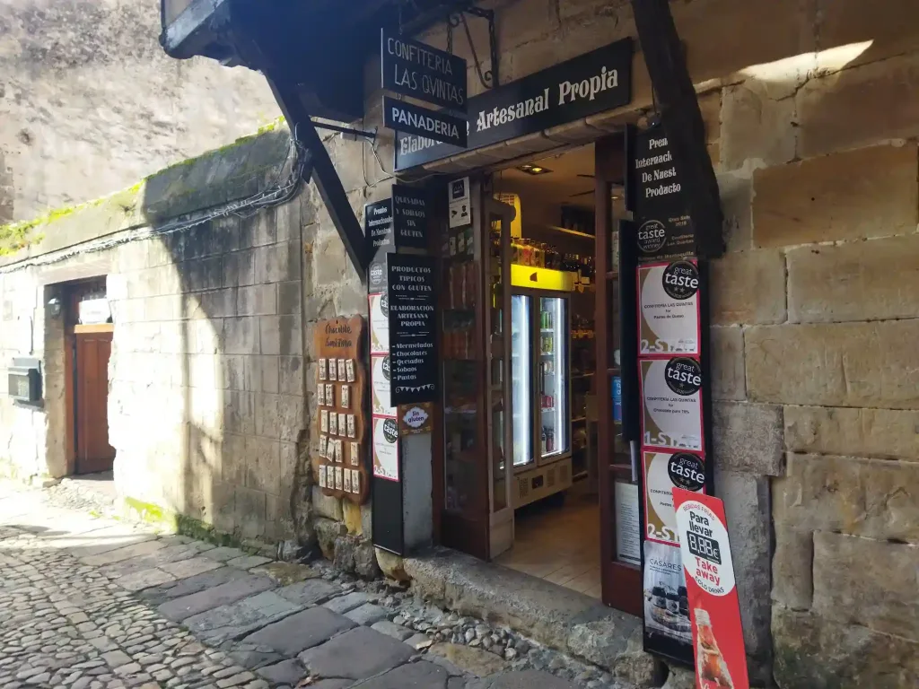 Edificio de piedra de sillería con una entrada de madera a una repostería sin gluten en Santillana del Mar