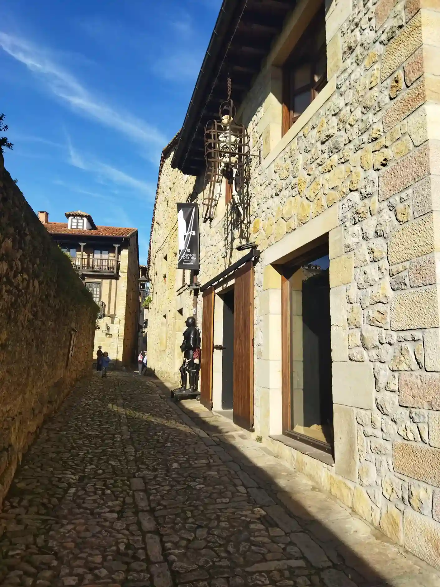 Edificio de piedra de sillería con una jaula negra colgada en la entrada con un esqueleto dentro 