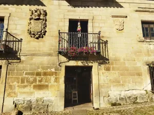 Edificio de piedra con un pinocho colgado del balcón en Santillana del Mar