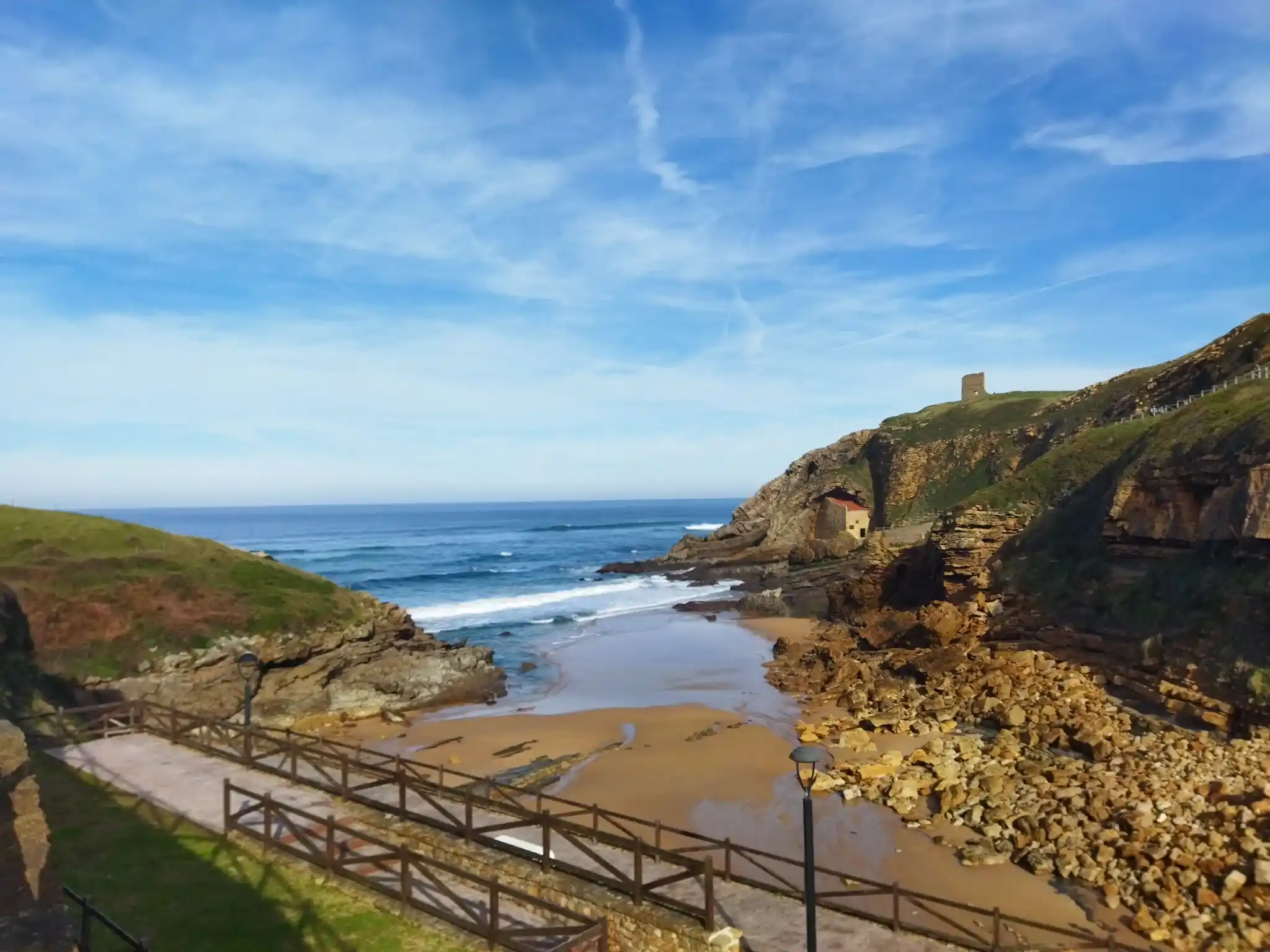 Playa con un paseo con barandilla en el primer plano en Santillana del Mar