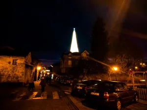 Conjuntos de edificios de piedra con algún coche en el primer plano. Al fondo se ve un árbol iluminado de Navidad gigantesco. Navidad Cantabria.