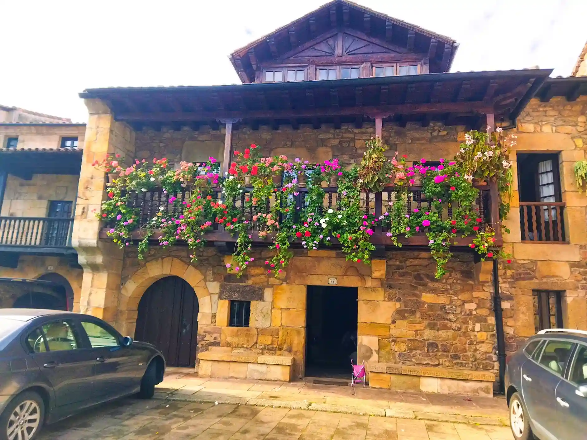 Casona de piedra y balcón con muchas flores rojas