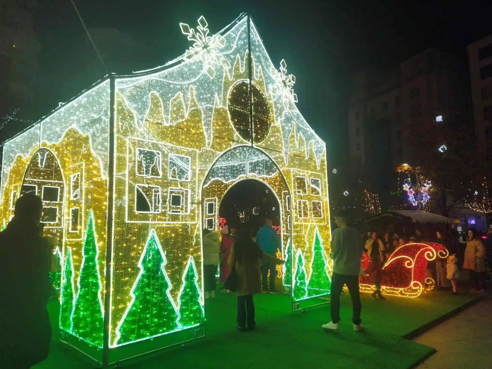 Casa iluminada con luces de navidad de color verde, amarillo y blanco.