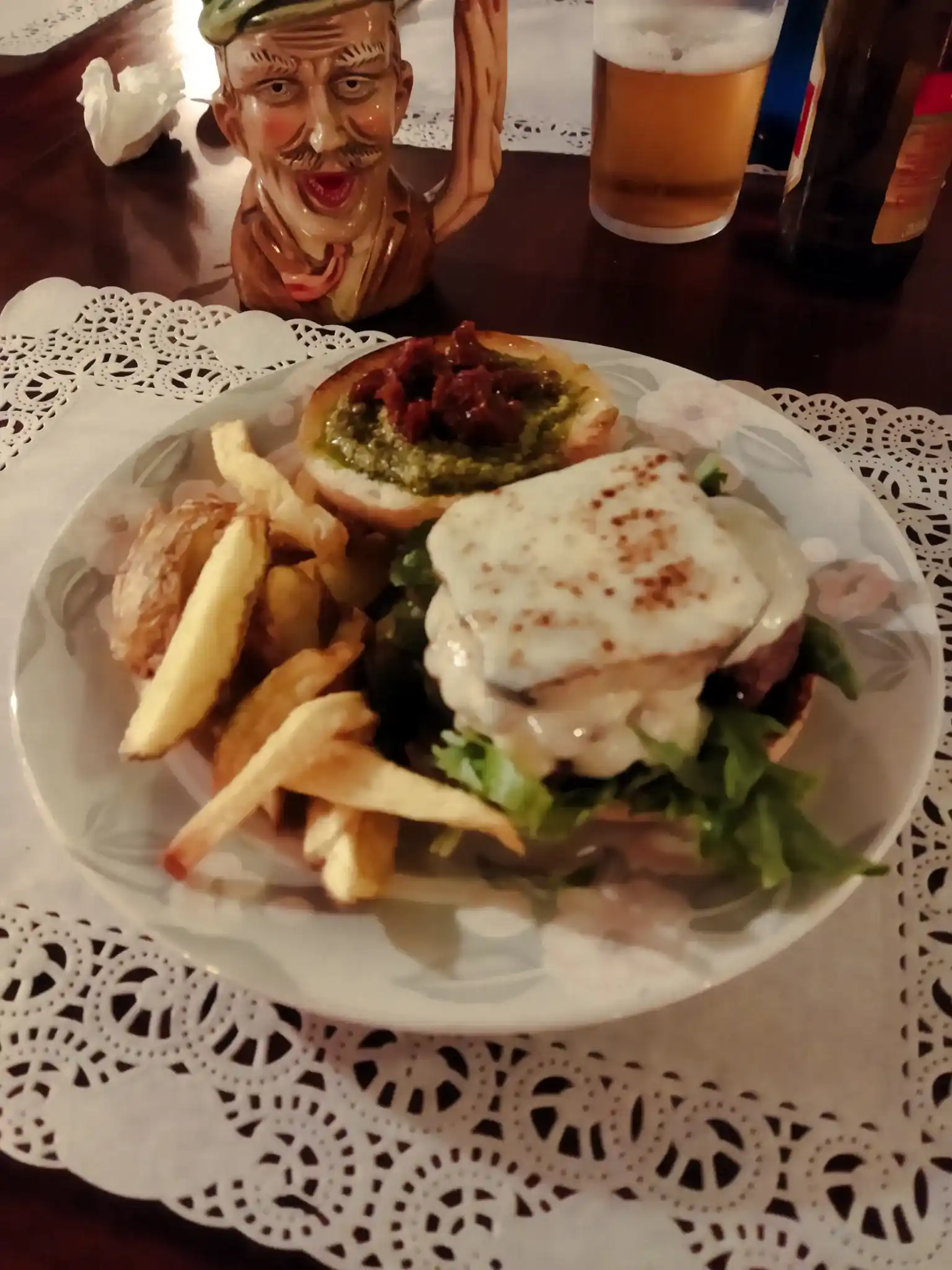 Hamburguesa con queso en un plato. Pan sin gluten. Cerveza sin gluten al fondo. Donde comer sin gluten en Cantabria.