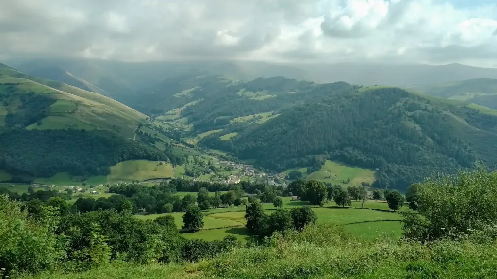 Paisaje de montes completamente verdes y un pueblo en el fondo del valle