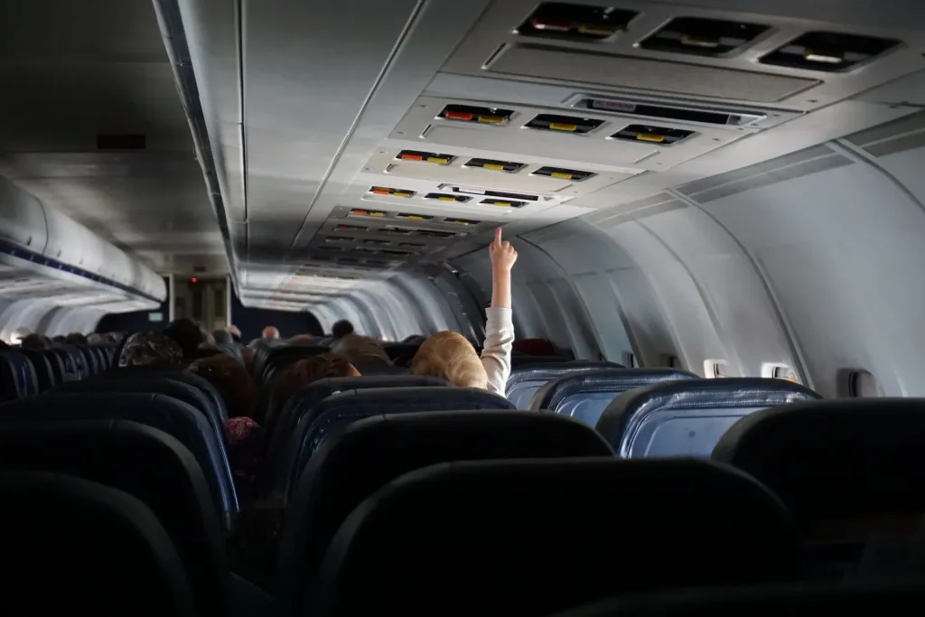 Niño intentando tocar el botón de llamada en un avión