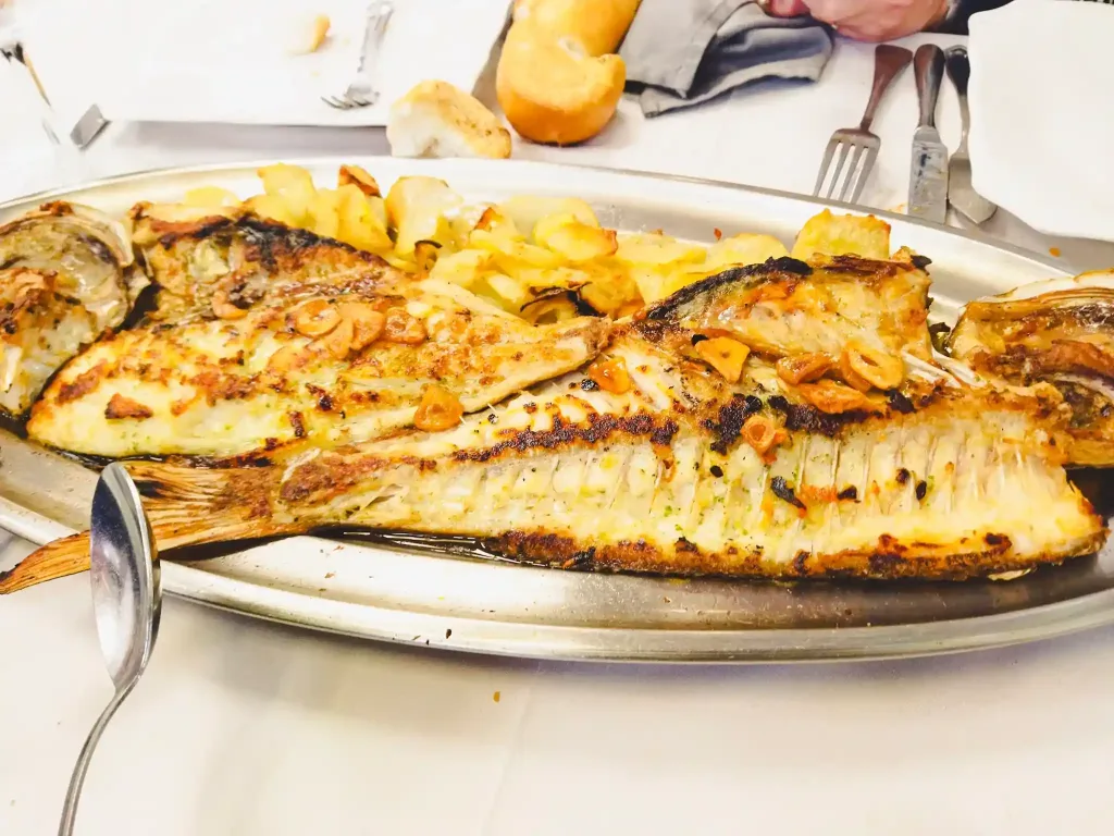 Pescado al horno con patata en una bandeja de acero inoxidable