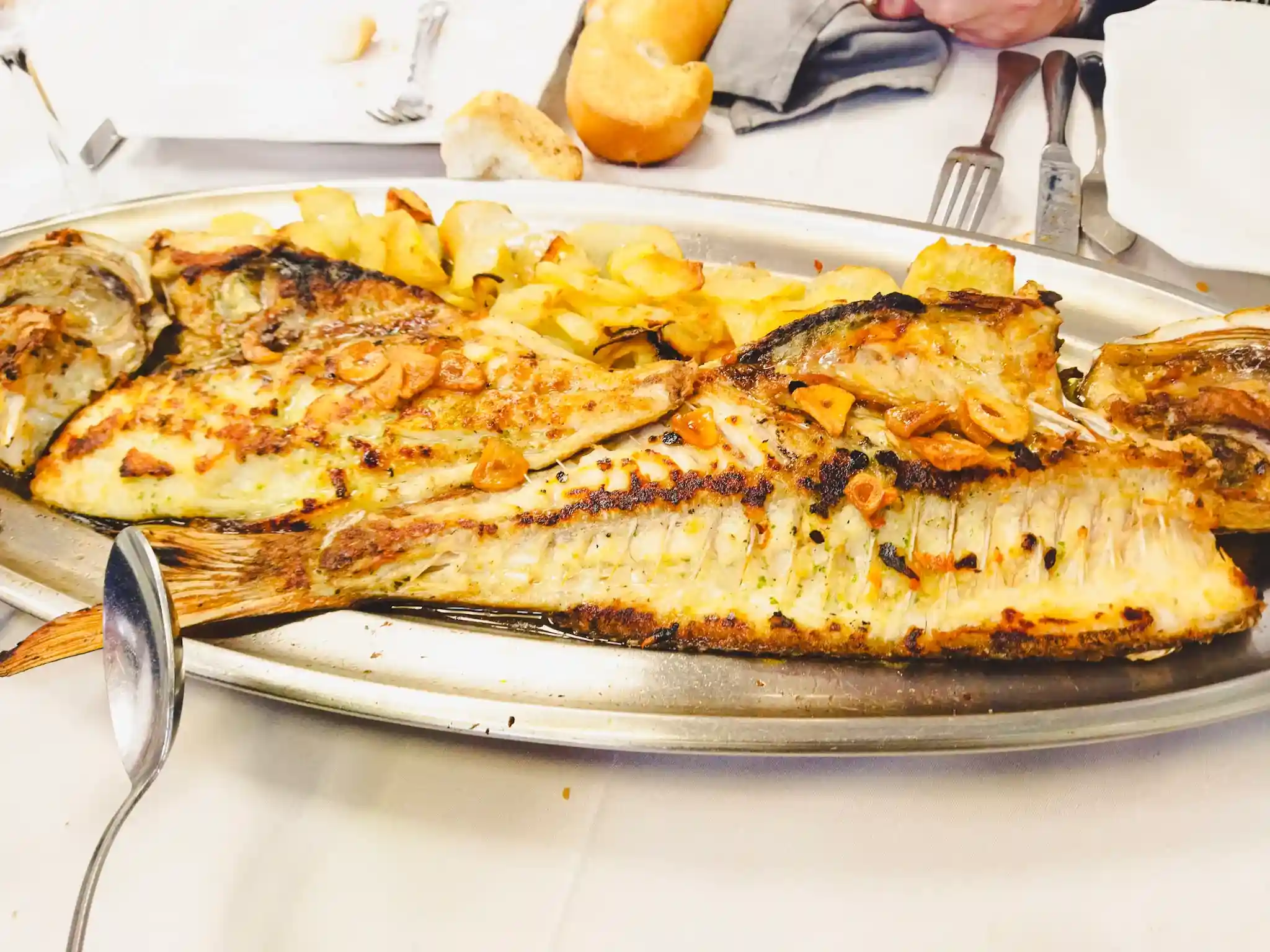 Pescado al horno con patata en una bandeja de acero inoxidable