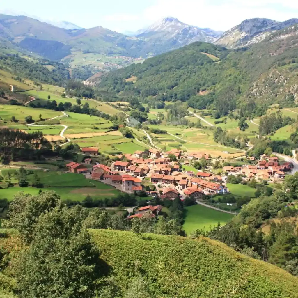 Valle de color verde y montañas con un poblado en medio