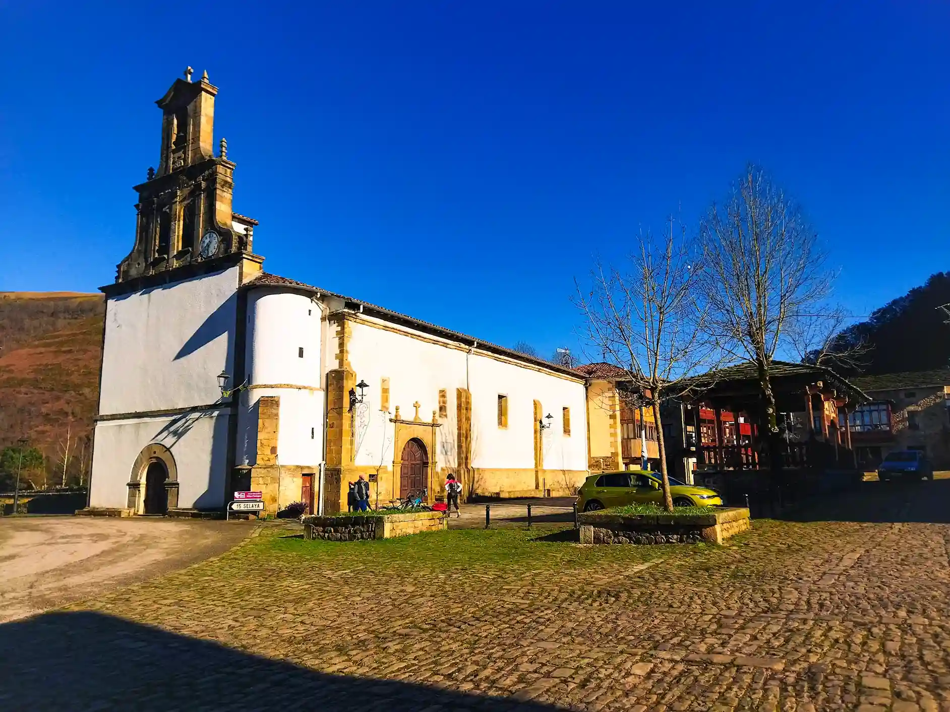 Iglesia de color blanco y suele empedrado. Ruta circular en coche por los valles pasiegos.