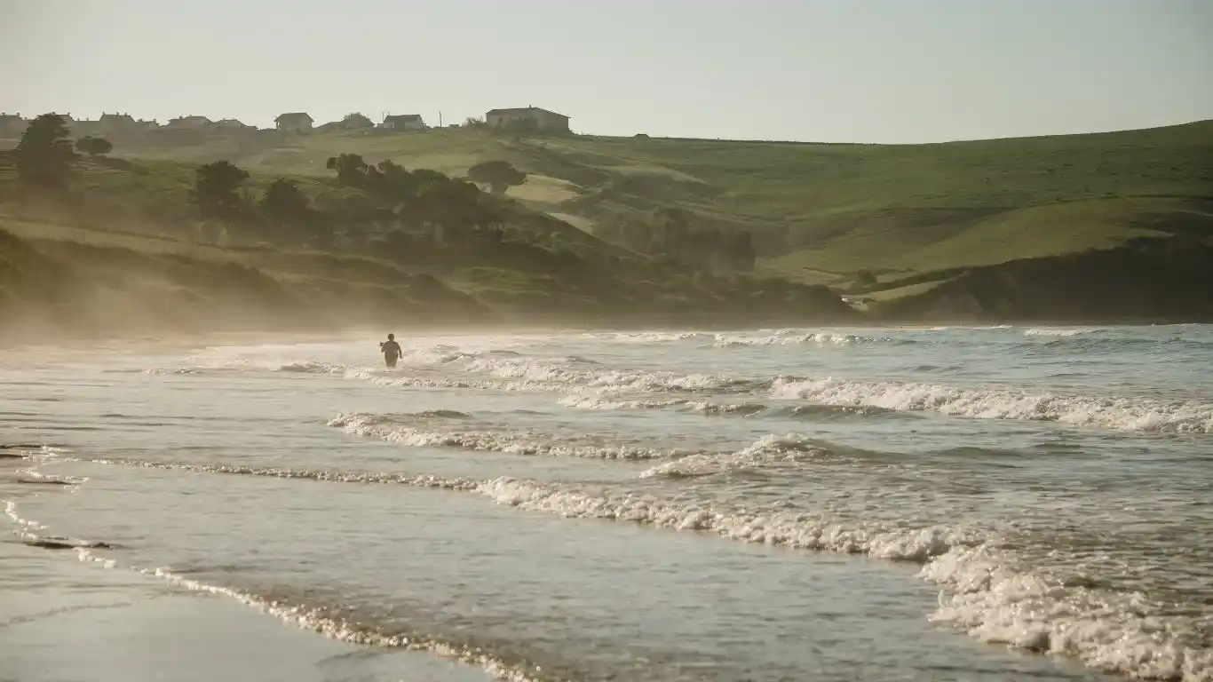 playa con olas y persona en el agua