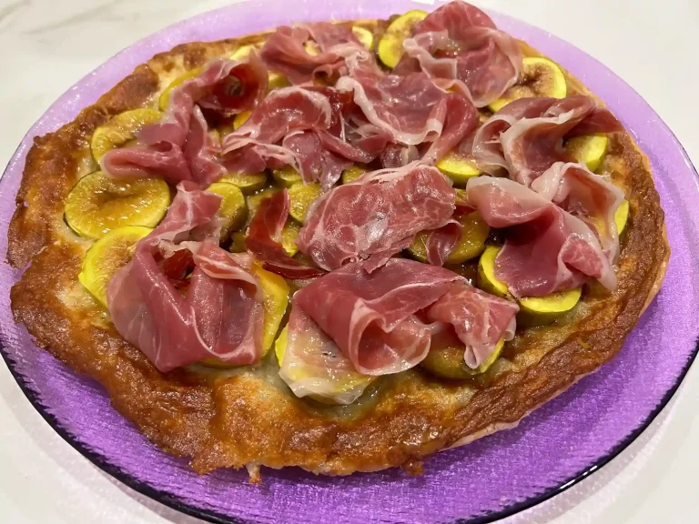 hojaldre sin gluten con higos, queso y jamón ibérico en un plato morado