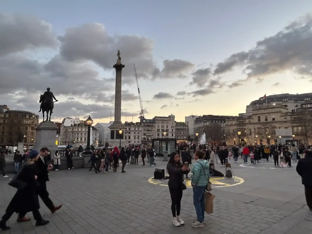 Plaza muy grande con mucha gente y una escultura en lo alto de una torre Trafalgar Square Fuente: glutendtrotters.com