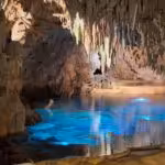 Galería de cueva con agua en calma reflejando la luz, similar al lago interior de la cueva de Chufín en Cantabria