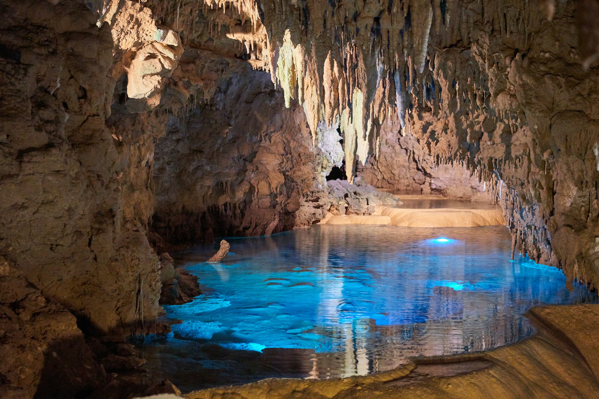 Galería de cueva con agua en calma reflejando la luz, similar al lago interior de la cueva de Chufín en Cantabria