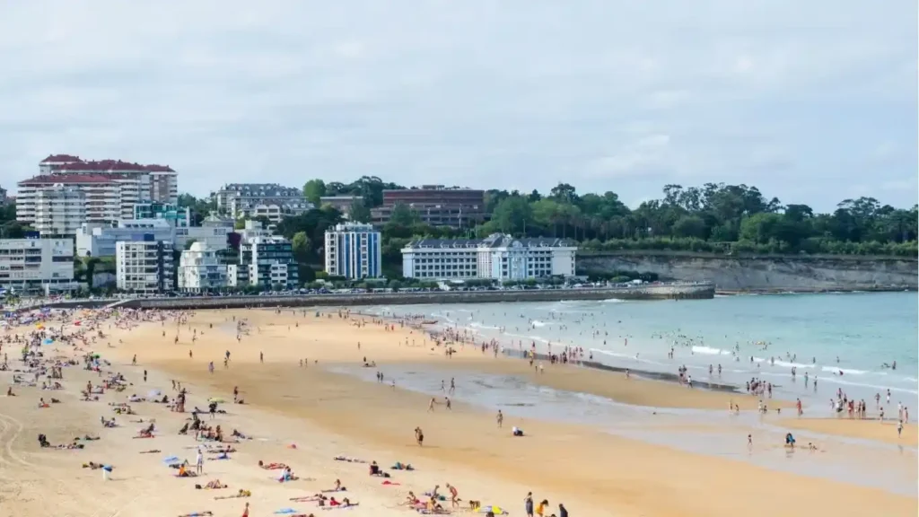 Foto de una playa con mucha gente y edificios al fondo. Semana Grande de Santander