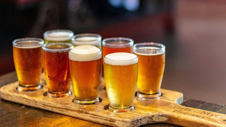 tabla de madera con 8 vasos llenos de cerveza