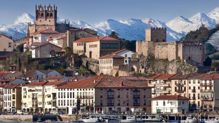 Panorámica de San Vicente de la Barquera con el castillo, la iglesia y los Picos de Europa nevados al fondo