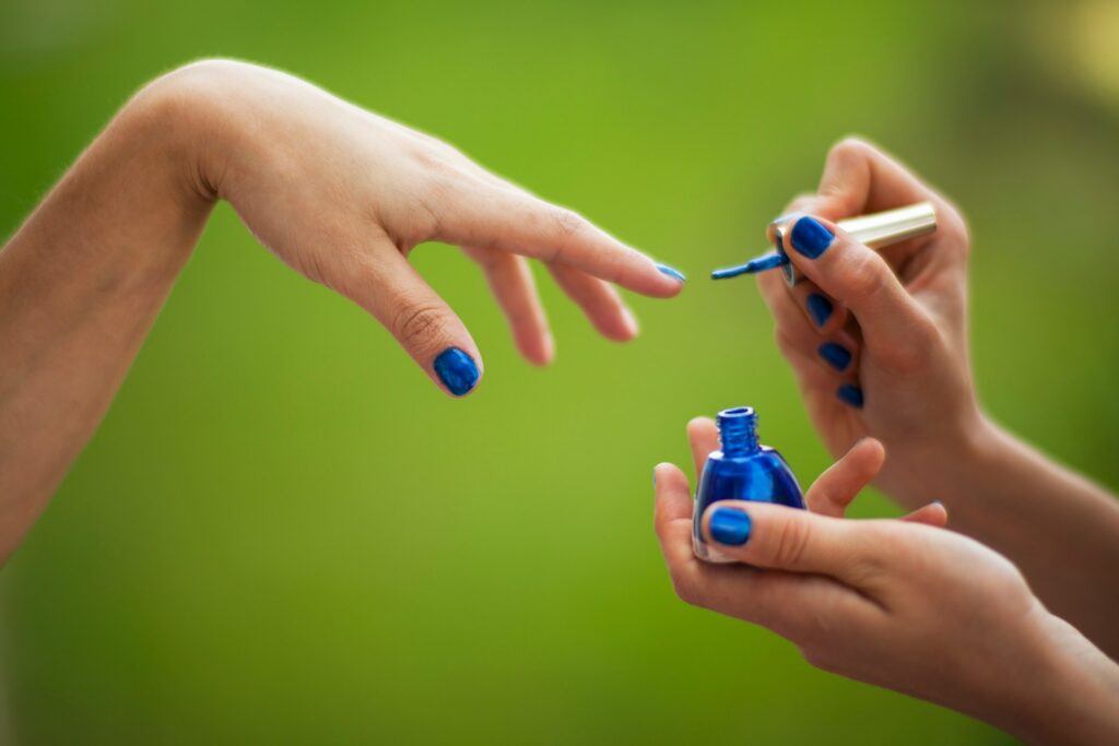 manos pintando uñas con una laca de uñas de color azul