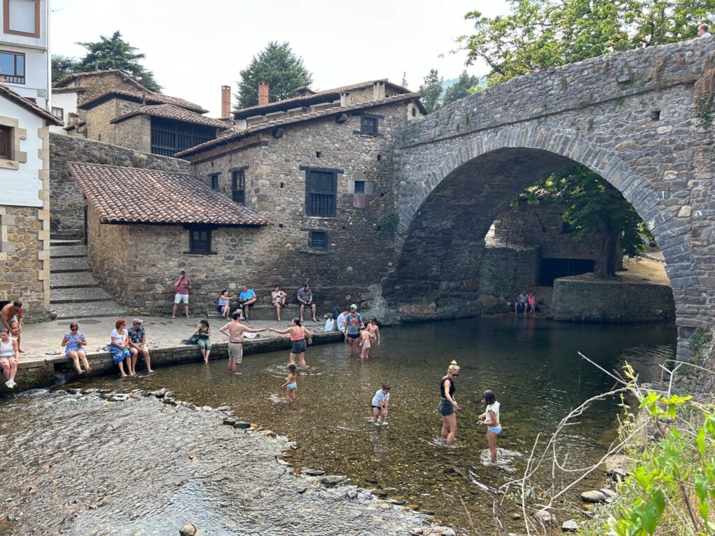Puente medieval y gente bañándose en el río